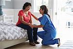 Nurse Making Home Visit To Senior Hispanic Woman