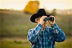 Farmer looking through binoculars on a paddock.