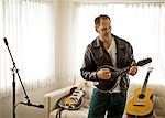 Mid-adult man playing a guitar in his living room.