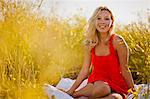 Portrait of woman in a red dress sitting in a meadow.