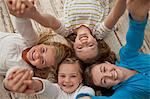 Portrait of four smiling sisters holding hands while lying close together on a hardwood floor.