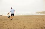 Father and daughter holding hands on a beach.