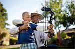 Mid adult man and his son holding a bow and arrow.