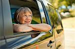 Happy senior woman looking out the window of a SUV.