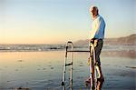 Portrait of a senior man standing on a beach with a walking aid.