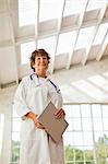 Confident female doctor holding documents and wearing a lab coat.