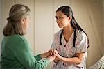 Smiling young nurse comforting a senior woman.