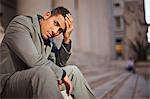 Young businessman looking worried while sitting outside.