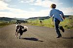 Excited boy and his dog running down a rural country road.