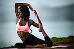 Smiling young woman practicing yoga on a beach.