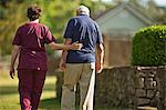 Mature nurse walking with a senior patient.