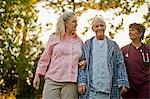 Portrait of a smiling senior man standing arm in arm with his wife and nurse.