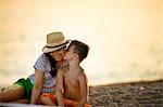 Boy kisses his mother's cheek  on the beach at sunset.
