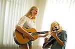 Happy teenage girls playing guitar together.