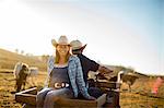 Portrait of a woman riding on the back of her husband's quad bike out on the ranch.