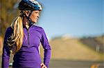 Young woman takes a break from cycling down a country road to admire the view.