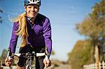 Portrait of a smiling young woman cycling down a country road.