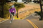 Focused young woman cycling down a lonely country road.