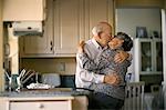 Affectionate elderly couple sneak a romantic kiss in the kitchen.