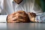 Elderly woman lays a comforting hand on her husband's arm.