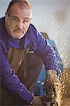 Portrait of welder cutting metal with electric tool in workshop