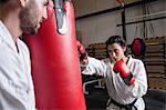 Man and woman practicing karate with punching bag in studio