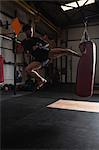 Boxer practicing boxing with punching bag in fitness studio