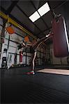 Female boxer practicing boxing with punching bag in fitness studio