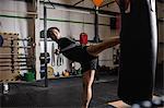 Boxer practicing boxing with punching bag in fitness studio