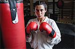 Portrait of woman practicing karate with punching bag in fitness studio