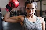 Portrait of female boxer in boxing gloves showing muscle in fitness studio