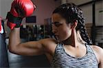 Female boxer in boxing gloves showing muscle in fitness studio