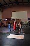 Female boxer practicing boxing with punching bag in fitness studio