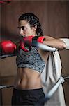 Tired female boxer in boxing gloves at fitness studio