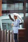 Beautiful woman holding umbrella and standing on street during rainy season