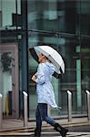 Beautiful woman holding umbrella and walking on street during rainy season