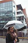 Portrait of beautiful woman holding an umbrella during rainy season on street