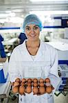 Portrait of female staff holding a carton of eggs in factory