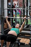 Pregnant woman lifting weights in gym