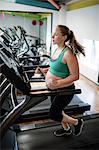 Pregnant woman exercising on treadmill at gym