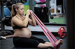 Pregnant woman exercising with resistance band in gym