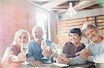 Portrait smiling couples toasting white wine glasses at restaurant table