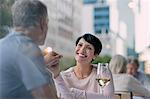 Affectionate couple holding hands and drinking white wine at urban sidewalk cafe