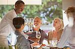 Waiter serving white wine to couples at restaurant table