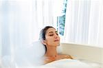 Serene woman enjoying bubble bath with eyes closed