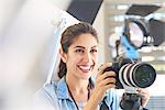 Smiling female photographer behind camera in studio