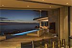 Illuminated home showcase patio with lap pool and twilight ocean view