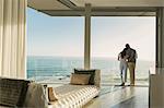 Affectionate couple hugging on sunny luxury balcony with ocean view