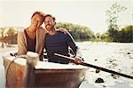 Portrait hugging couple canoeing on sunny lake