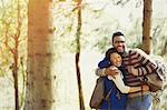 Playful couple with backpacks hugging hiking in woods